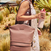 Woman with Willow breast pump bag over shoulder holding a portable breast milk cooler