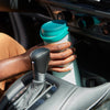 Teal portable breast milk cooler sitting in a car cup holder