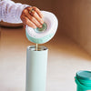 Person pouring breast milk from a pump into a portable breast milk cooler